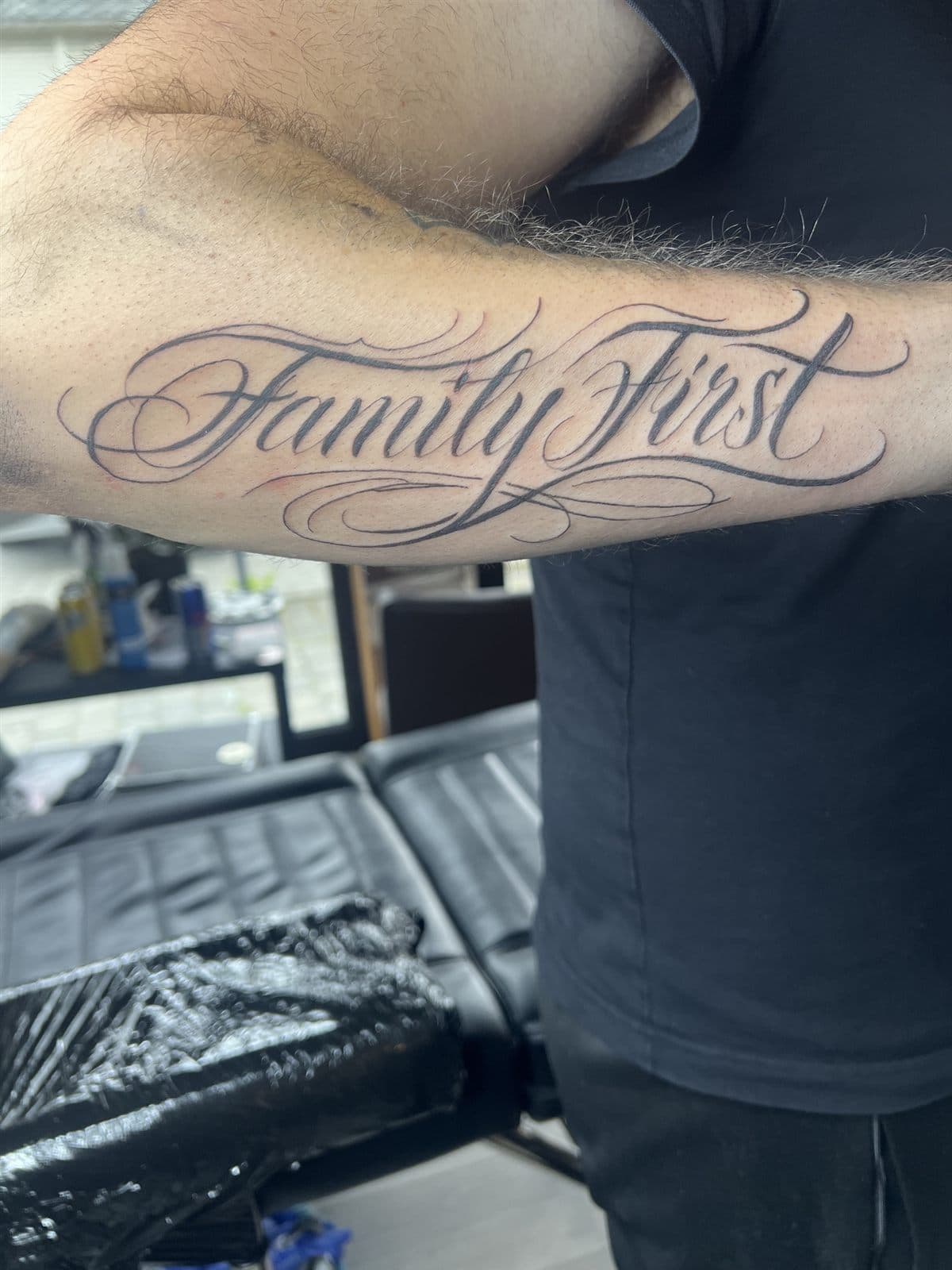 Family First i script-lettering på underarm